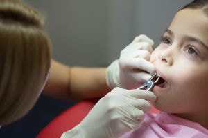 Процесс удаления молочного зуба у ребенка